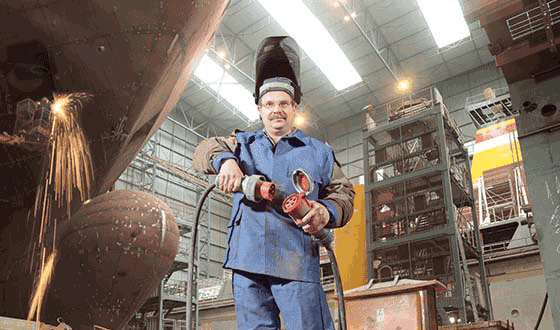 A construction worker of a shipyard in a blue overalls puts together the MENNEKES connector and the plug